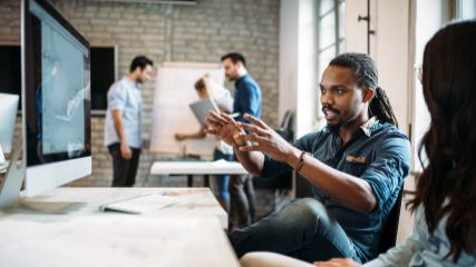Man presenting from computer screen to a woman