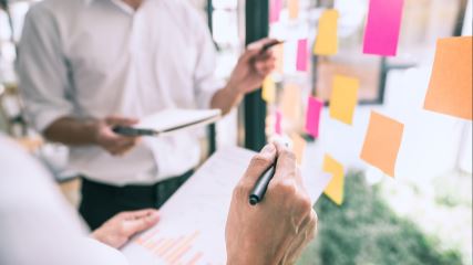 People writing on post-it notes placed on a window