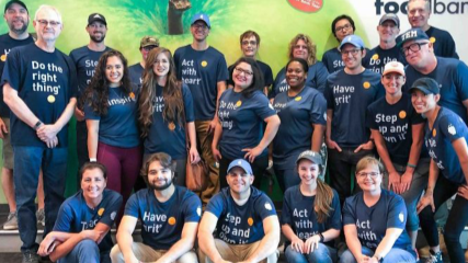 A square picture of Margo picking up a box while volunteering at the Houston Food Bank.