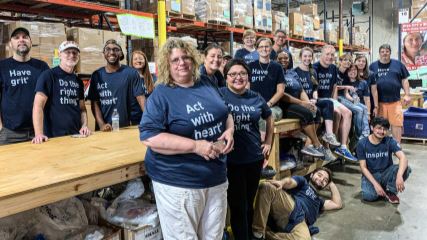 The BrandExtract team standing against tables at Project C.U.R.E. trailer.