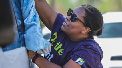 Tia washing a car while volunteering