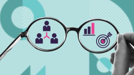 A photograph of glasses being help up to a blurry graphic in the background. Through the glasses you can see clearer, where there are icons representing employee connectedness and high performance