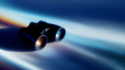 Binoculars resting on the ground with brilliant blue and white light shining through