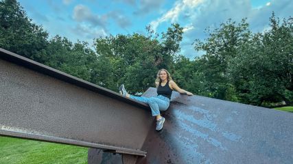 Ylliana leaning on a metal structure outside in the summer