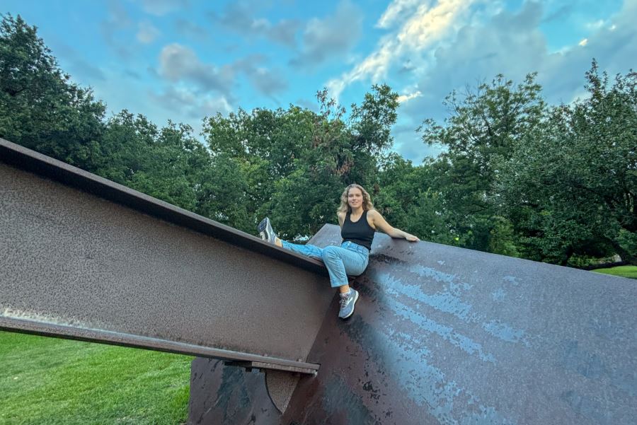 Ylliana leaning on a metal structure outside in the summer