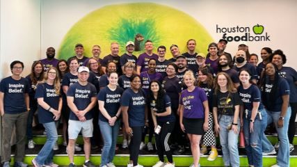A photograph of the BrandExtract team standing in front of a wall at the Houston Food Bank.