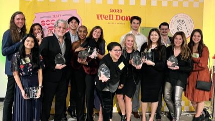 BrandExtract team posing in front of a backdrop holding a total of ten awards