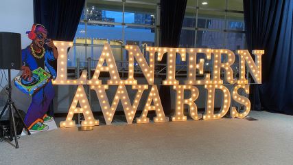 Photograph of large light-up letters spelling "Lantern Awards" against a window