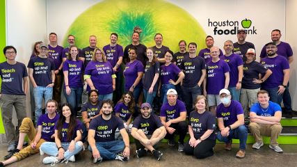 entire BE team, wearing purple t-shirst, in front of a green backdrop at the Houston Food Bank