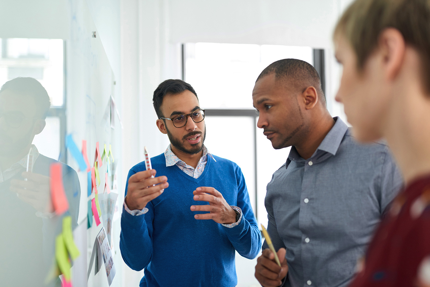 Three people holding a discussion at a whiteboard