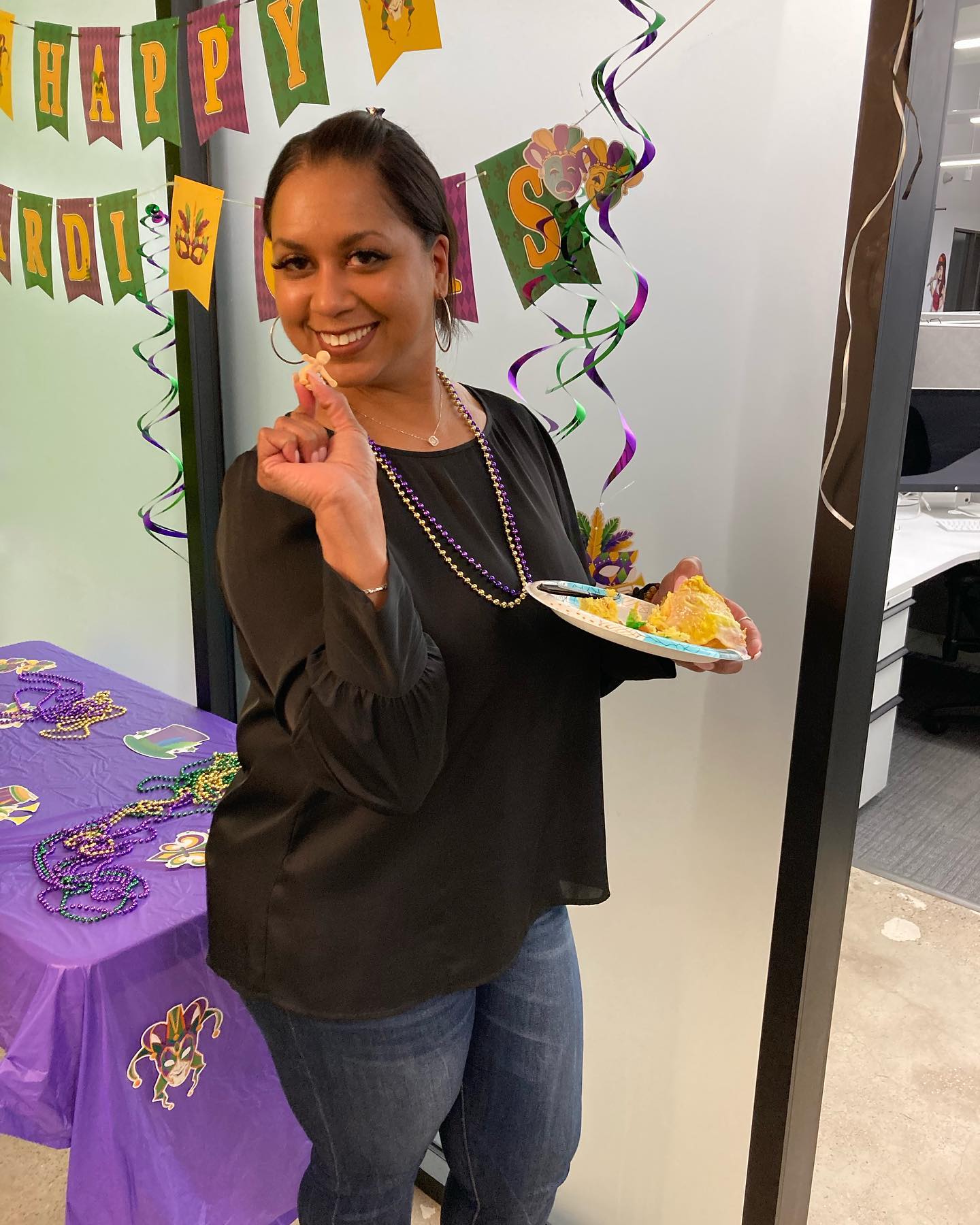 Karen smiling and holding up the baby at BrandExtract's Mardi Gras celebration