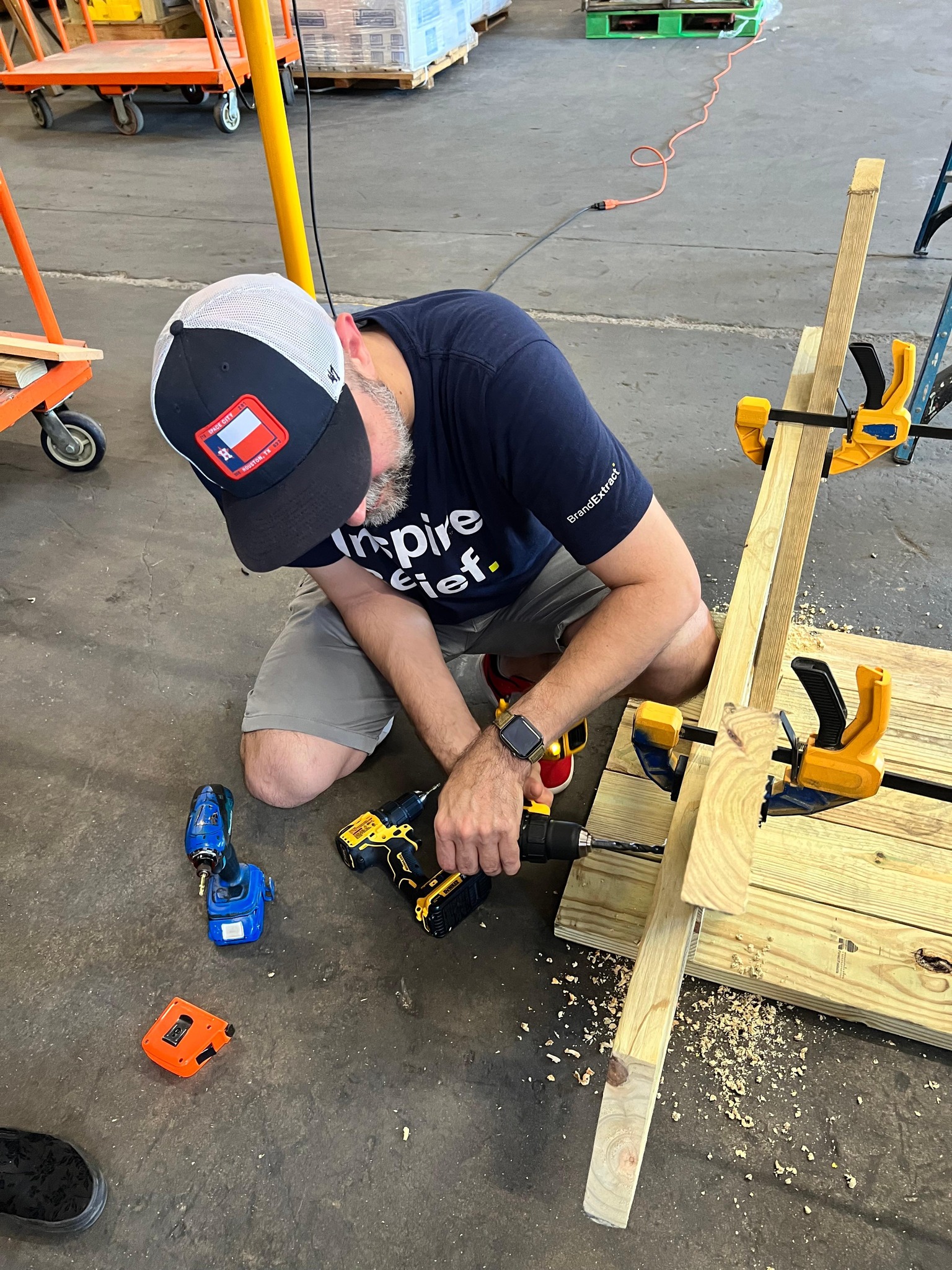 Jason drilling a hole in a table during a volunteer event at the Houston Toolbank