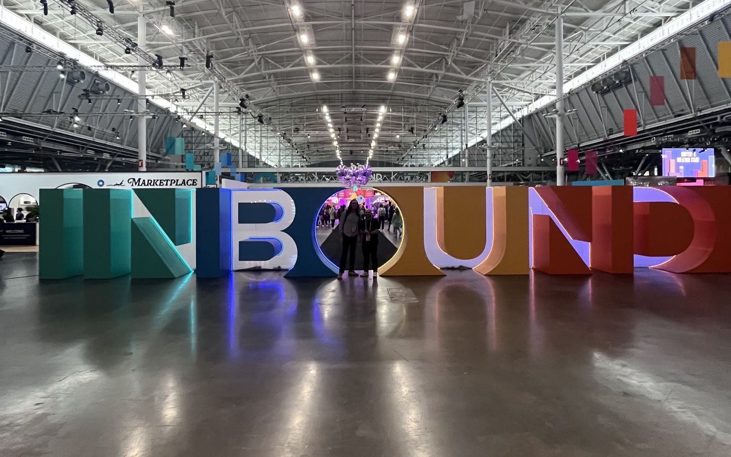 A photograph of Taylor and Chris standing in front of massive block letters spelling out "INBOUND" at the 2024 Inbound conference in Boston.