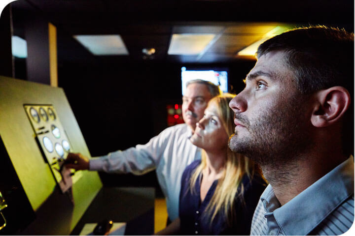 Three Superior employees watching a monitor.